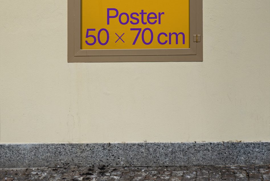 Wall-mounted poster mockup in urban setting, 50x70 cm size indicator, visible frame, ideal for outdoor advertising design preview.