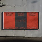Urban billboard mockup on metal wall featuring three red panels with Mockup Maison text, dimensions display for design presentation.