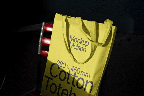 Bright yellow cotton tote bag mockup on shopping cart, high contrast lighting, realistic branding presentation, 380x450mm design asset.