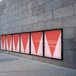 Urban poster mockup on a wall with modern architecture, showcasing geometric design posters with red gradients, ideal for presentations.