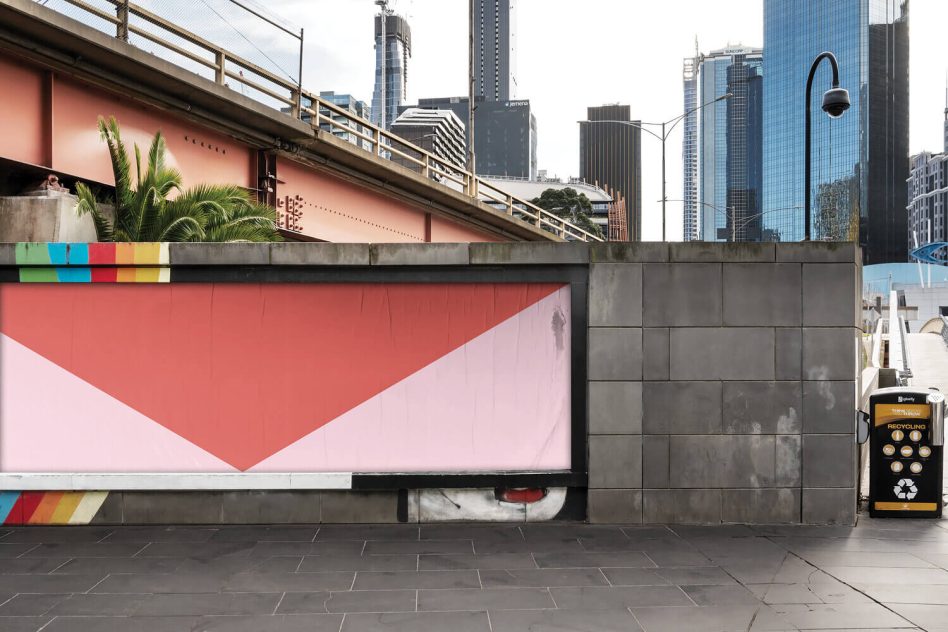 Urban billboard mockup on city street with large blank red and white advertising space for designers to showcase graphics and posters.