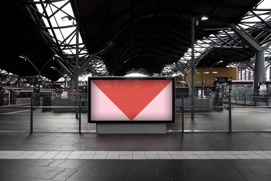 Digital billboard in transit hub showing downward pointing red triangle composition