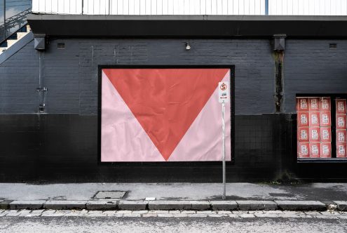 Urban billboard mockup on black brick wall with a red and white poster design, street setting for realistic advertising presentations.