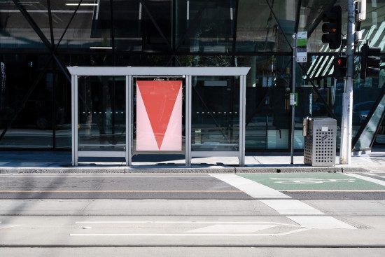 Urban bus stop poster mockup with geometric graphic design, showcasing clear print visibility for outdoor advertising in a city setting.