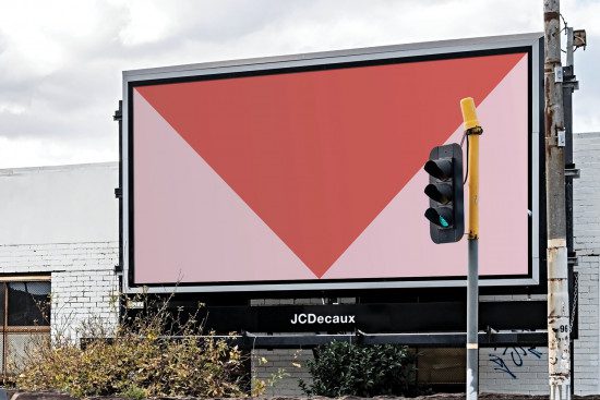 Billboard mockup with red and pink design on urban roadside, traffic light in view, suitable for advertising display. Perfect for designers' presentations.