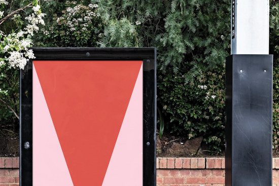 Outdoor advertising mockup with blank poster space on a metal frame surrounded by lush greenery, ideal for graphic designers to showcase work.