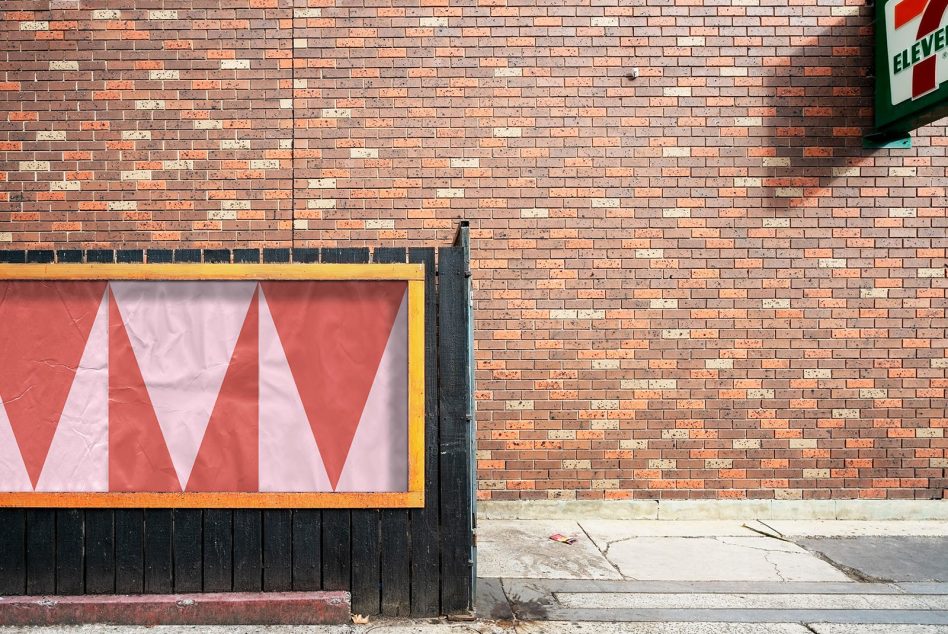 Three red triangles repeating pattern in yellow frame against exposed brick wall