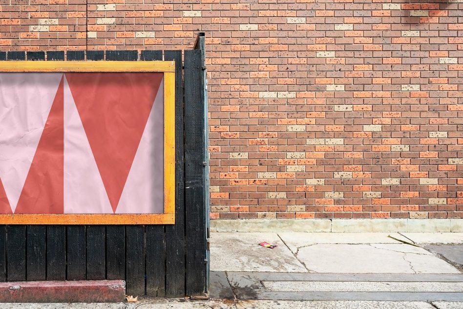 Single red triangle shape in yellow-framed window on weathered brick storefront