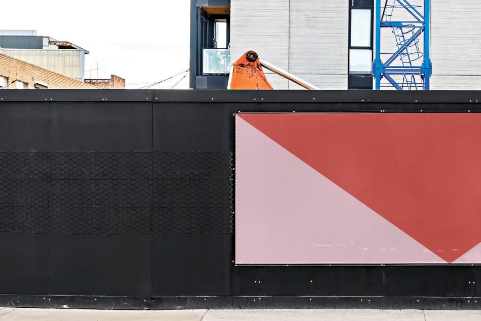 Diagonal billboard mockup with coral triangle split composition on industrial black wall