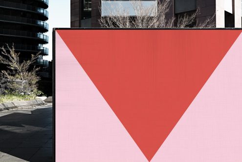 Urban billboard mockup with red triangular graphic for outdoor advertising in modern cityscape, designers' mockup template.