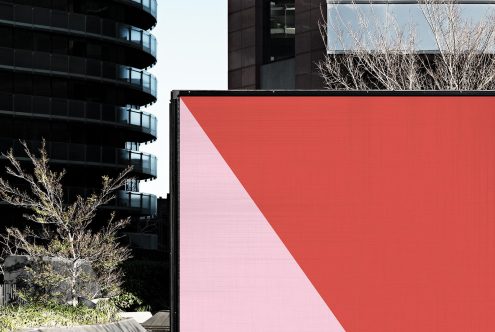 Urban billboard mockup on the side of a building for outdoor advertising design presentation, with clear blue sky.