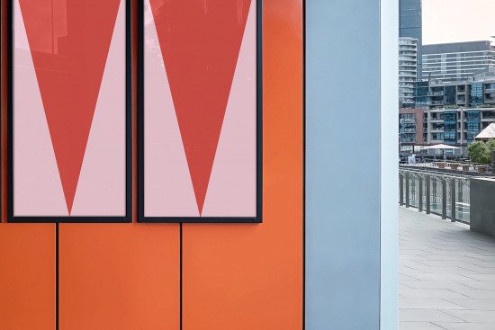 Urban poster mockup with geometric design on an orange wall against cityscape for designers and advertisers to showcase work.