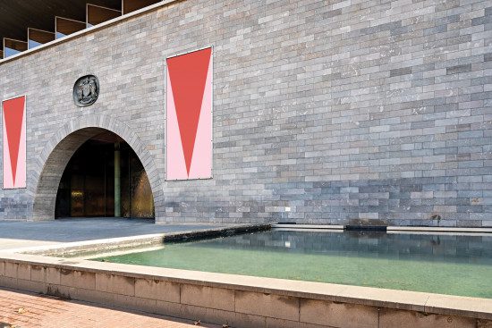 Modern building wall with blank red banners for mockup designs, stone texture, arch entrance, and reflection pool, ideal for advertising templates.