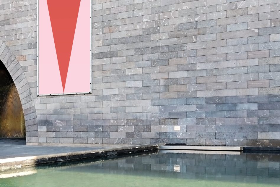 Vertical poster mockup on slate brick wall above reflecting pool