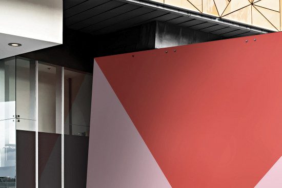 Modern office building corner with geometric wall design, presenting a mix of red and grey panels for architecture mockup.