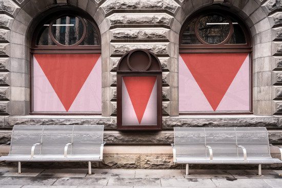 Stone building facade with symmetrical windows featuring red triangle posters, suitable for graphics mockup templates.