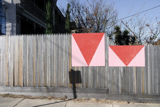 Urban street art mockup with geometric red triangles on weathered wooden fence, ideal for showcasing graffiti or outdoor advertising designs.