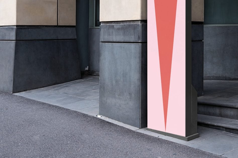 Modern sign with tall red triangle on light pink background between dark concrete walls
