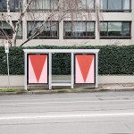 Urban bus stop billboard mockup with minimalist red graphic design poster, street setting with greenery and clear signage.