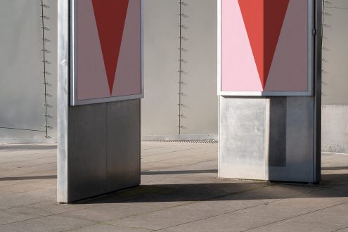 Outdoor billboard mockup with minimalist red and pink triangle design in an urban setting, ideal for presenting advertising graphics.