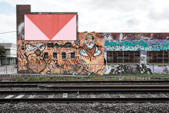 Urban street art graffiti on building with vibrant colors, texture, and railroad tracks, ideal for realistic mockups or urban themed graphic design.