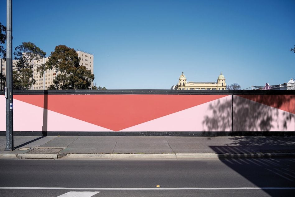 Street level view of red pink inverted triangle pattern on public fence