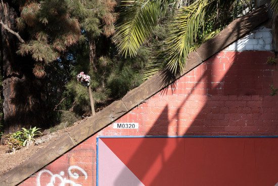 Urban scene with shadow on red brick wall, geometric shapes, graffiti, textured surfaces for graphics or template design inspiration.