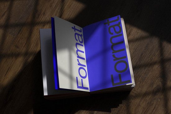 Open magazine mockup on wooden surface with dramatic shadows, showcasing modern font design, perfect for presentations and portfolios.