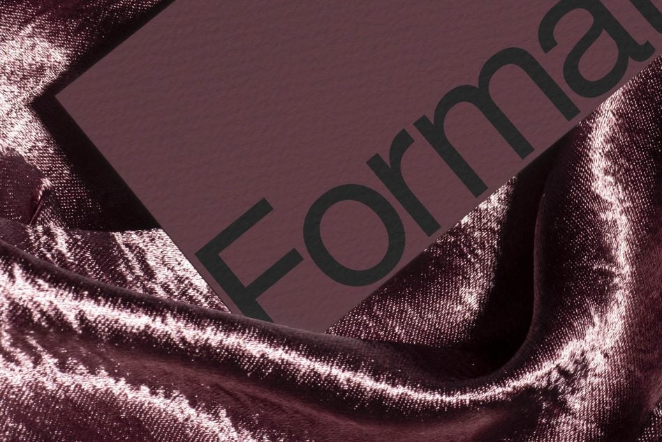 Burgundy card with dark text resting on shimmering metallic fabric closeup