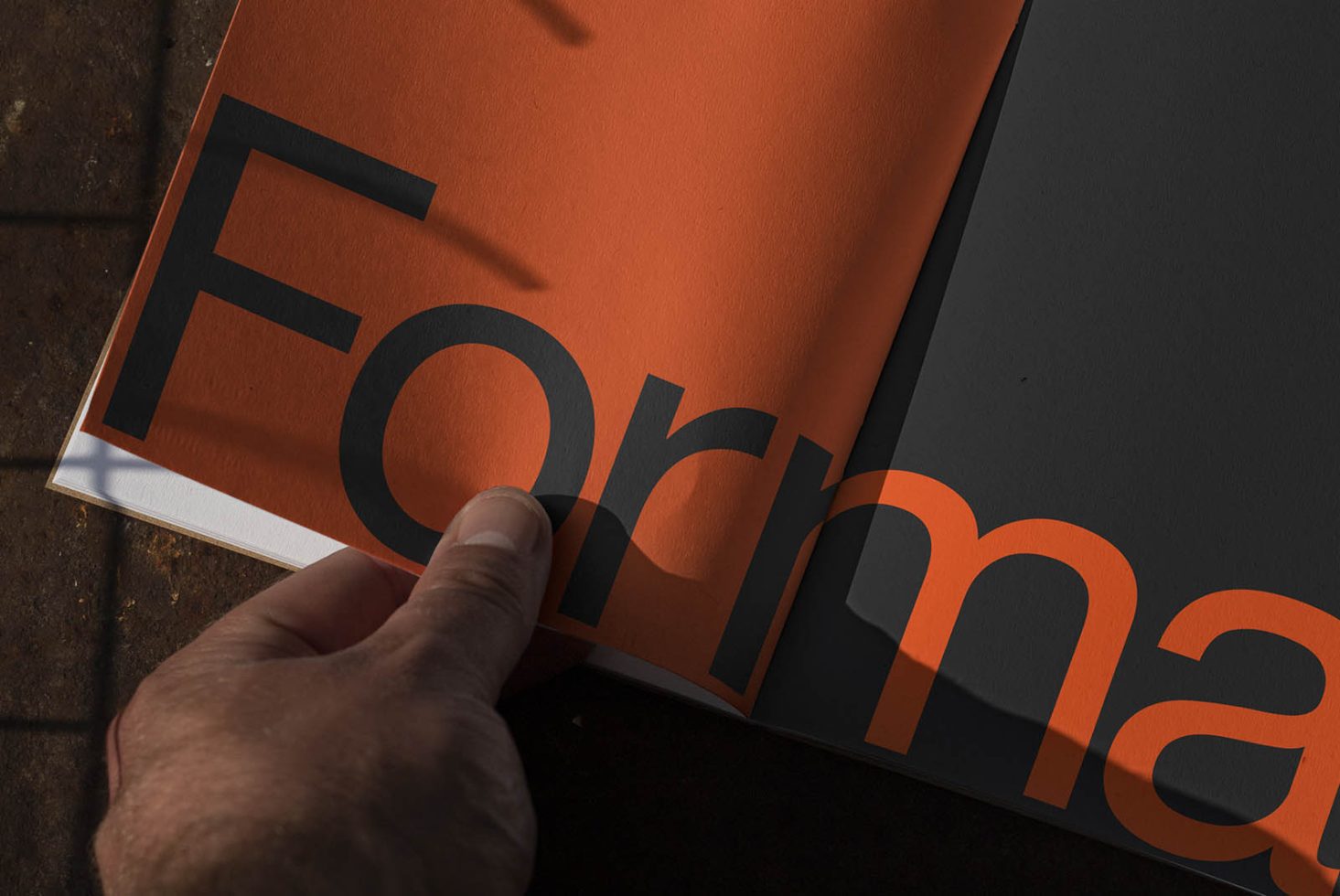 Close-up of hand turning page in a modern font design book, ideal for designers seeking typography inspiration or font mockup textures.