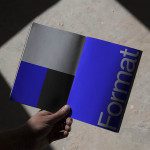 Hand holding a magazine mockup with bold typography design cast in natural shadow light, ideal asset for graphic presentation.