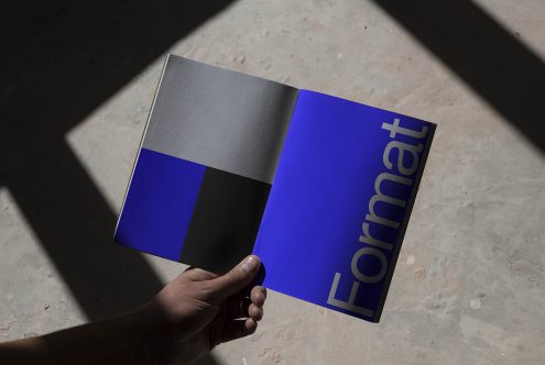 Hand holding a magazine mockup with bold typography design cast in natural shadow light, ideal asset for graphic presentation.