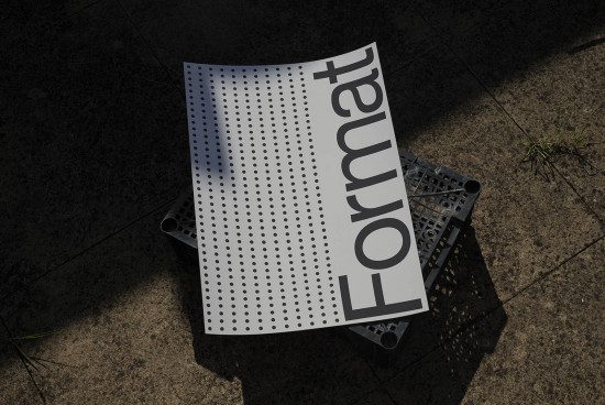 Poster mockup with curled edges lying on urban ground, casting a shadow, featuring bold typography design, ideal for presentation.