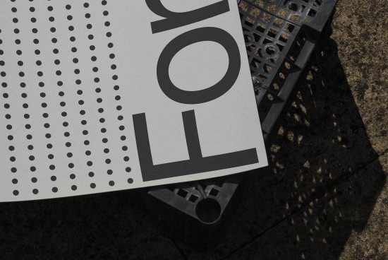 Close-up view of bold typography poster mockup with dotted pattern, leaning against an industrial crate, textured background, natural lighting.