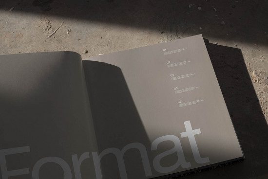 Open magazine mockup on concrete surface with dramatic shadow, showcasing layout design and font style for designers.