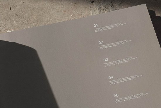 Printed document mockup with numbered text layout, natural shadow, and concrete surface for graphic designers presentations.