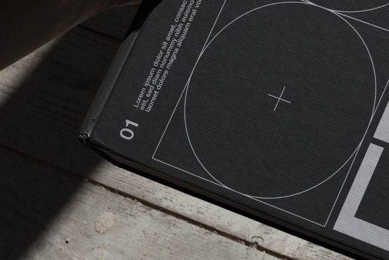 Book mockup on wooden surface with shadow, close-up on black cover with white graphic design elements, realistic texture, design asset.