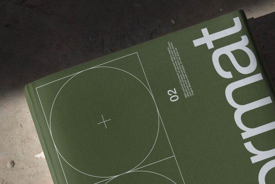 Top view of green magazine cover mockup with white geometric design and typography on a dark textured surface for graphic design assets.
