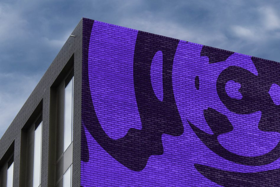 Large-scale glyphic mural in purple projected on modern building facade