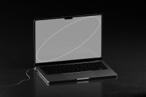 Laptop tilted showing neutral gray screen with white curved line graphic
