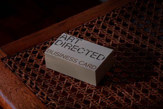 Elegant stack of business cards mockup with 'Art Directed' text on woven texture background, showcasing design in natural light for branding.
