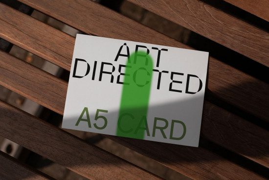 A5 card mockup with typography art directed on wooden bench, realistic shadows, graphic design asset for presentations.