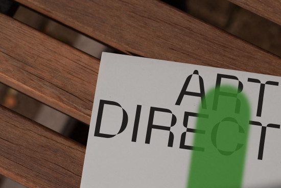 Paper with the text "Art Direct" on a wooden bench, graphic design mockup, for designers, clear fonts, creative overlay, professional presentation.