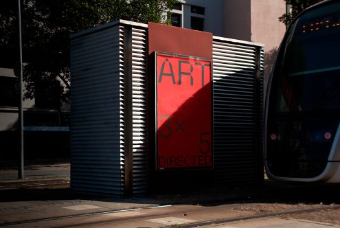 Urban street art poster on a metal kiosk with a tram passing by, suitable for mockup graphics, dynamic city life design theme.