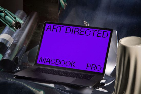Laptop mockup for art directors with vibrant screen, amidst creative clutter, ideal for digital asset design presentations.