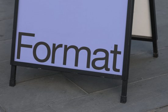 A-frame sidewalk signboard mockup with customizable text area displaying the word 'Format', on a city street background for designers.