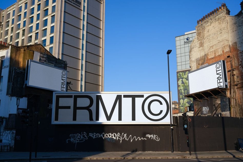 Large FRMTO sign on urban street with graffiti wall below against mixed architecture
