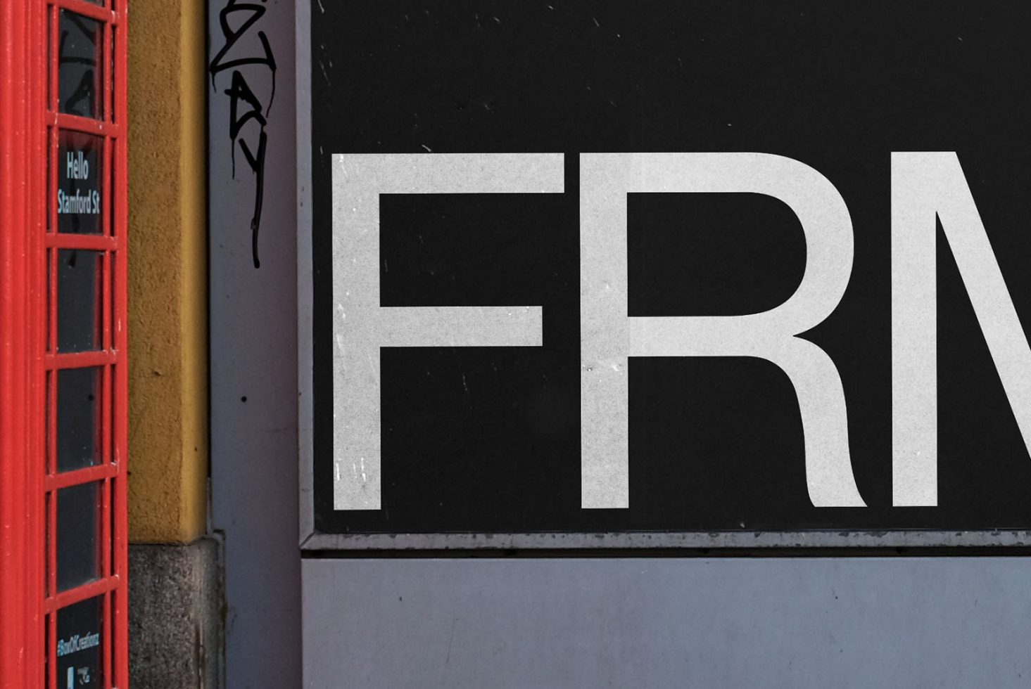 Close-up view of urban typography design, featuring bold white letters on a black background next to a vibrant red phone booth.