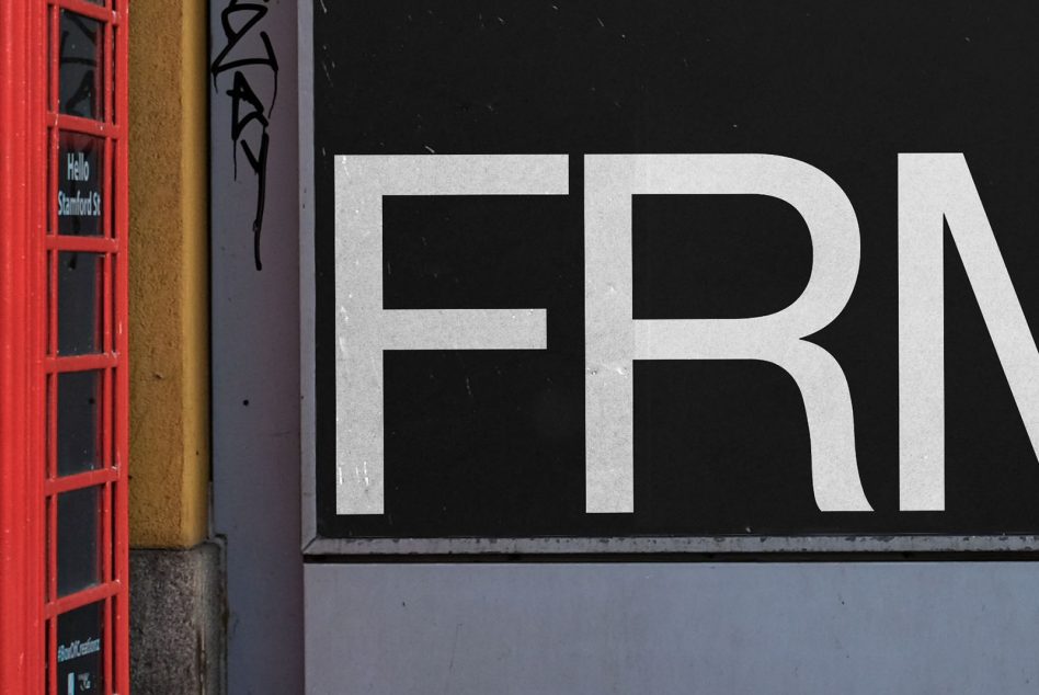 Large white letters spelling FRN on black storefront with red British phone booth nearby