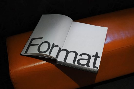 Open magazine mockup on a leather sofa showcasing bold typeface design, ideal for presentations and design assets.